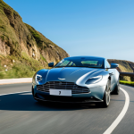 **

A sleek Aston Martin DB11 Hybrid, fully clothed, gliding along a winding coastal road. Background: blue ocean sparkling in the sunlight, clear sky, lush green cliffs. Style: professional automotive photography, dynamic angle, showcasing the car's elegant design. safe for work, appropriate content, professional, modest, perfect anatomy, correct proportions, natural pose, well-formed hands, proper finger count, natural body proportions.

**